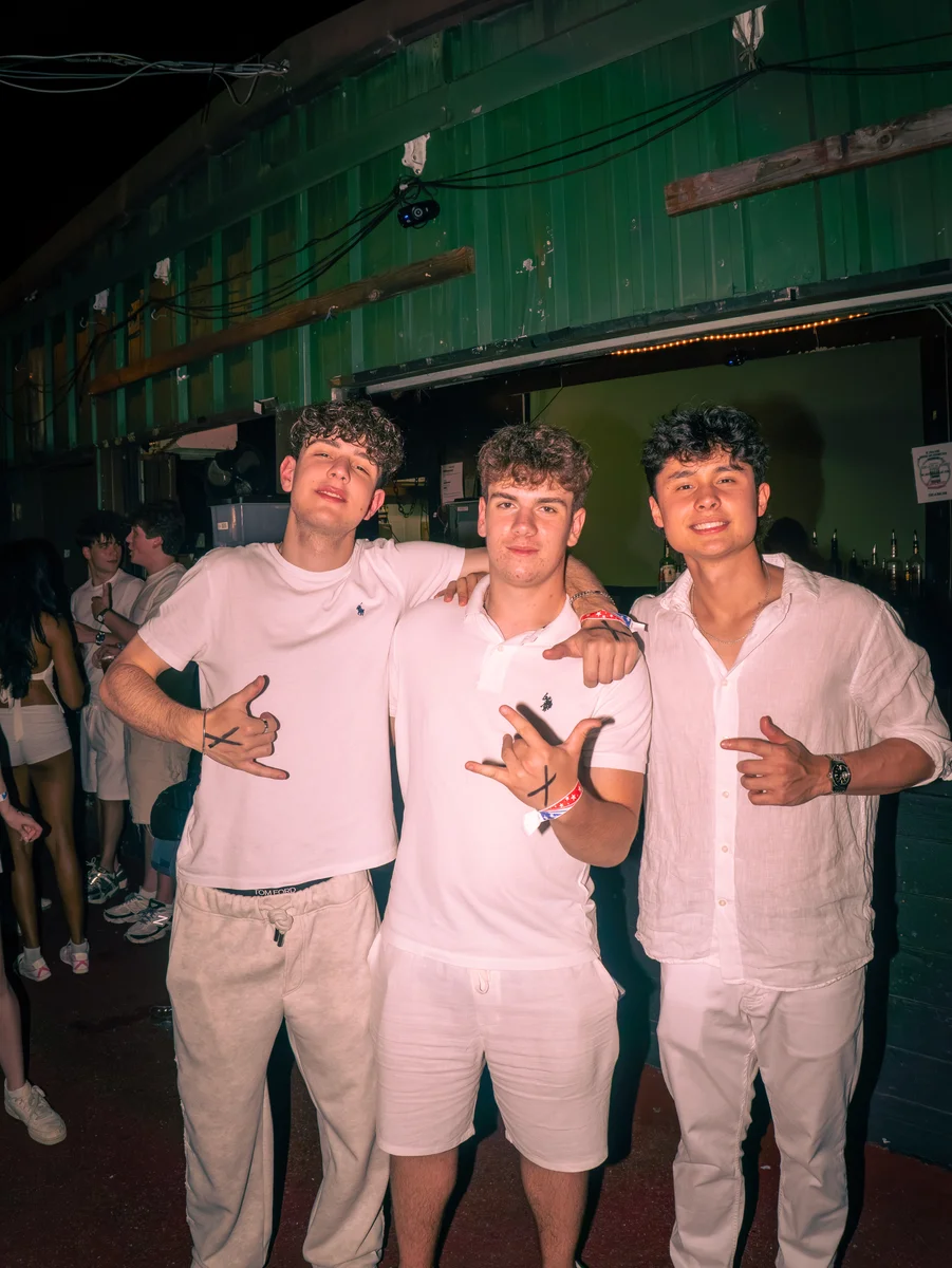 Three guests dressed in white at a nightlife event